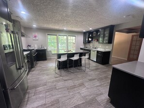 Een moderne keuken met een centraal eiland, barkrukken en een ingebouwde vaatwasser.