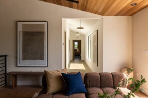 A modern living room with a sofa, a bench, and a large abstract painting. - Hesby Grand Maison By Alora Reserve (Los Angeles)