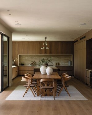 Une cuisine moderne avec des meubles en bois, un îlot central et un coin repas avec des chaises.