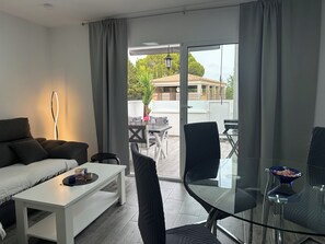 Een moderne woonkamer met een bank, een glazen tafel en uitzicht op het buitenterras.
