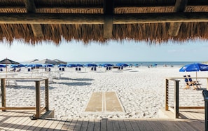 Una playa con sombrillas, sillas de descanso y una terraza de madera.
