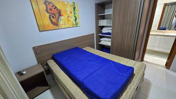 Un dormitorio con cama, mesita de noche, armario y un cuadro en la pared.