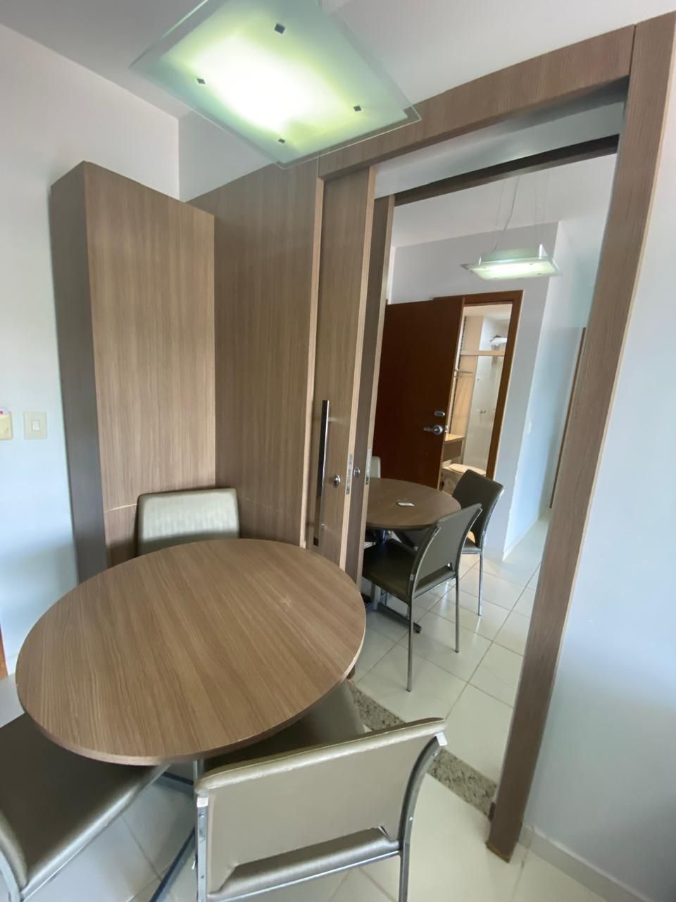 Un comedor con una mesa redonda y sillas, un armario de madera y una puerta que da a otra habitación.