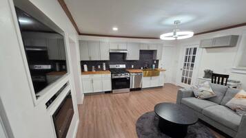 A modern kitchen with white cabinets, a black countertop, and a stainless steel range hood.