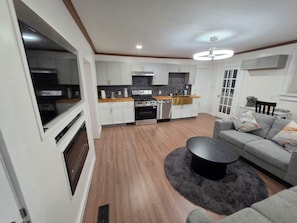 A modern kitchen with white cabinets, a black countertop, and a stainless steel range hood.