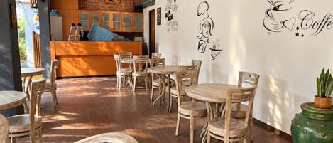 A café interior with wooden furniture, a brick wall, and wall art.