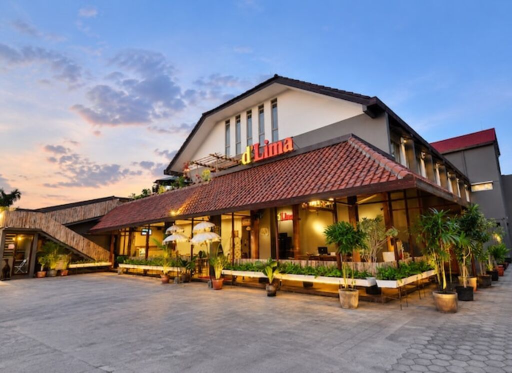 Un hotel con tejado de baldosas, zona de estar exterior y plantas en macetas.