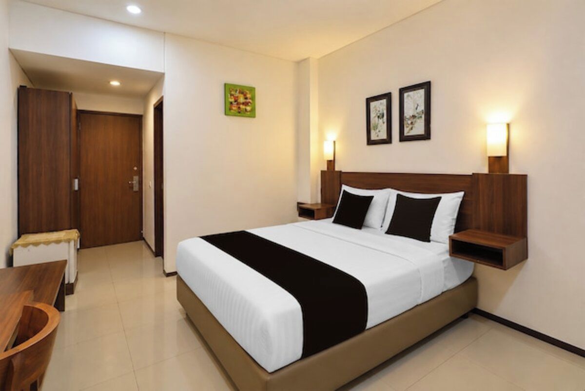 A hotel room with a bed, bedside tables, a desk, and a wardrobe.