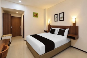 Una habitación de hotel con cama, mesitas de noche, escritorio y armario.