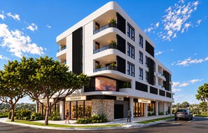 Un immeuble moderne à plusieurs étages, doté de balcons, d’une enseigne indiquant le nom d’une entreprise, et avec un ciel dégagé.