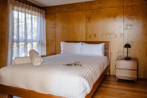 A neatly made bed with white linens and pillows, a bedside lamp, and a wooden nightstand. - Oystercatcher Bicheno - Private track to the beach! (Glamorgan-Spring Bay)