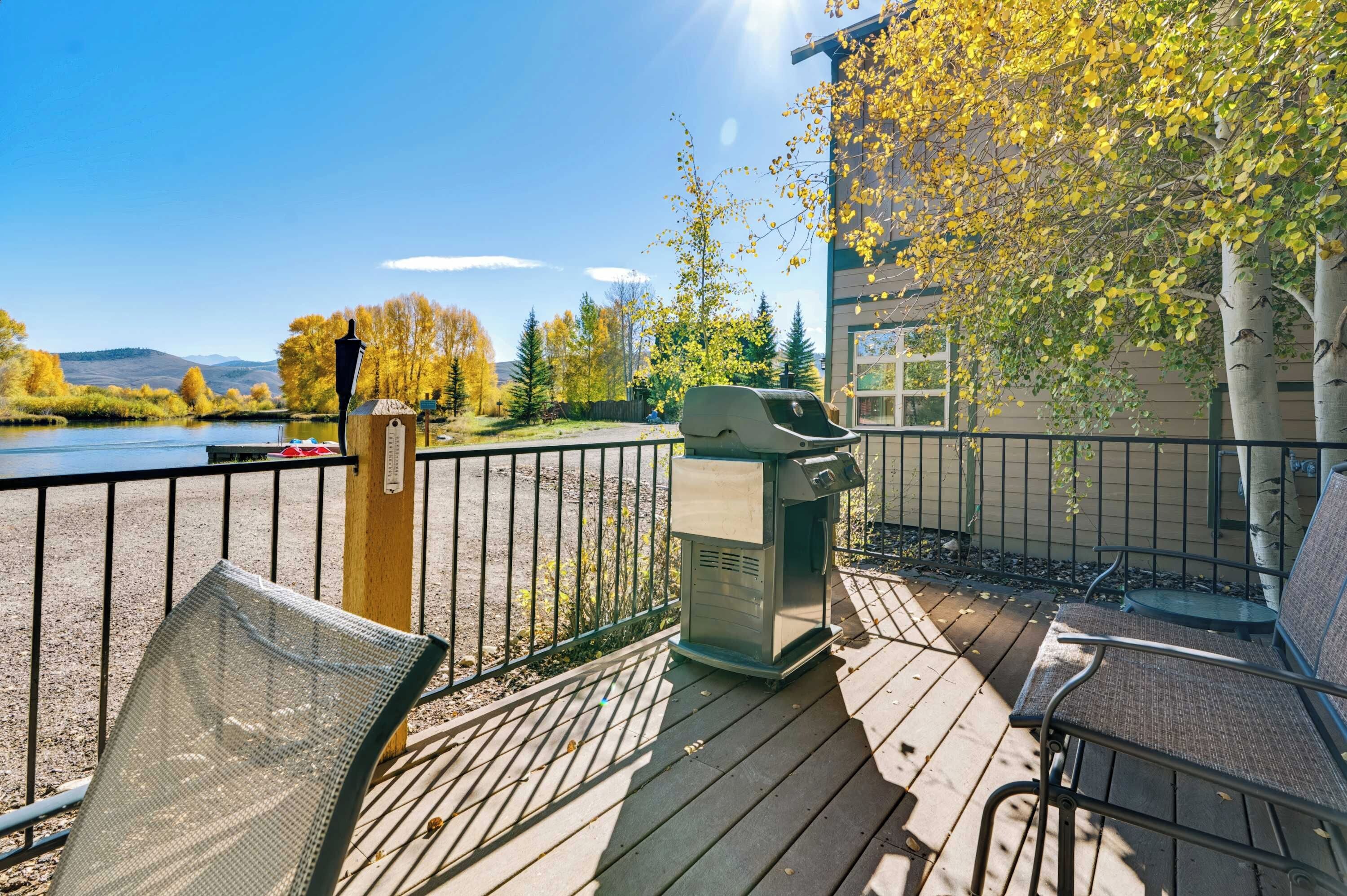 Una terraza con mobiliario exterior, una parrilla y vistas a un lago y montañas.