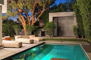 A modern outdoor pool area with a built-in seating arrangement and a large tree. - Fuller Celestia By Alora Reserve (Los Angeles)
