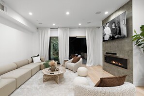 Ein stilvolles Wohnzimmer mit einer Couch, Sesseln, einem Couchtisch und einem Kamin.