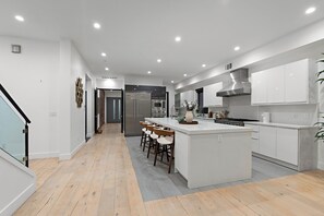 Eine moderne Küche mit einer zentralen Kochinsel, Barhocker und Edelstahlgeräten.