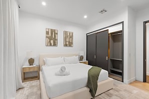 A modern bedroom with a large bed, bedside tables, a wardrobe, and abstract wall art. - Fuller Celestia By Alora Reserve (Los Angeles)