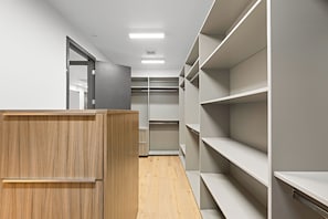 Ein begehbarer Kleiderschrank mit Holzsäulen und Metallregalen.