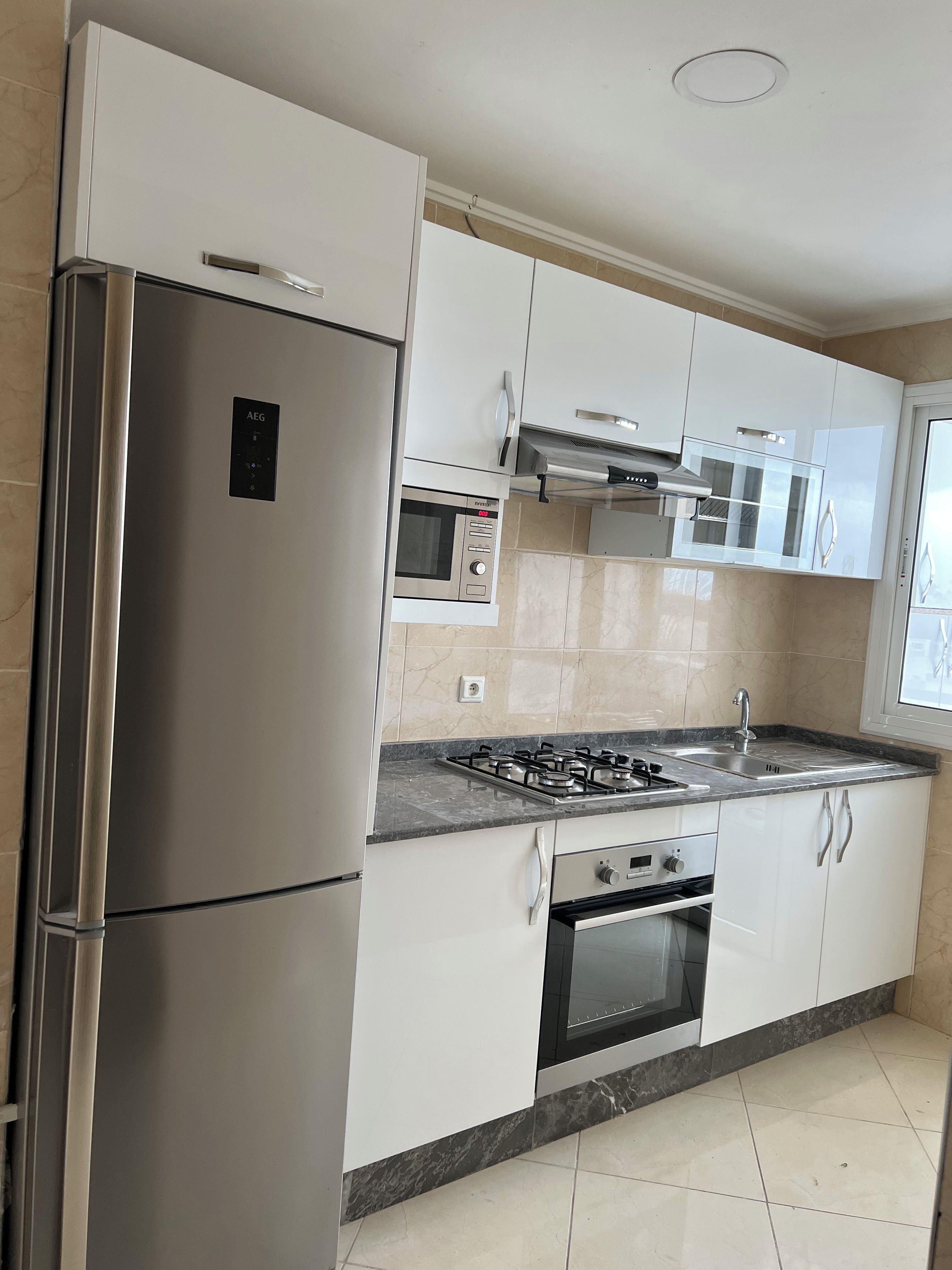 A modern kitchen with stainless steel appliances, a gas stove, and white cabinetry.