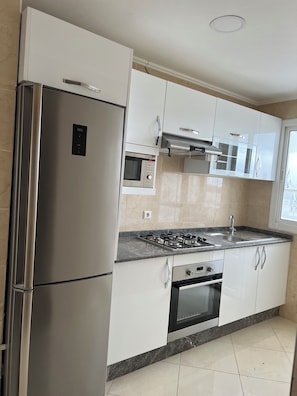 A modern kitchen with stainless steel appliances, a gas stove, and white cabinetry. - New Listing (Tanger)