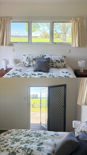 Une chambre à coucher avec un lit, deux lampes de chevet, une fenêtre avec des rideaux et une porte donnant sur l’extérieur.