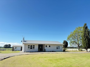 A single-story house with a front porch, a satellite dish, and a well-maintained lawn. - Clareville Farmhouse - Relax in Peaceful Rural Surroundings Near the Showgrounds (Clareville)
