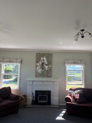 A living room with a fireplace, two sofas, and a horse painting on the wall. - Clareville Farmhouse - Relax in Peaceful Rural Surroundings Near the Showgrounds (Clareville)