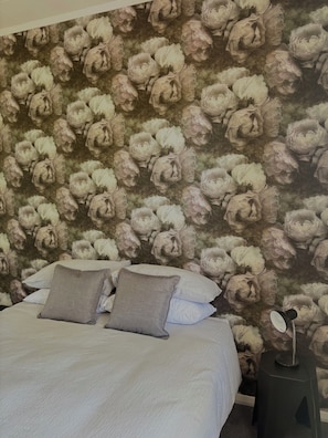 A bedroom with a floral wallpaper, a bed with white bedding and two pillows, and a bedside table with a lamp. - Clareville Farmhouse - Relax in Peaceful Rural Surroundings Near the Showgrounds (Clareville)