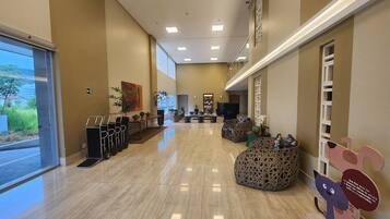 Um hall amplo com piso lustroso, áreas de estar e um balcão de recepção.