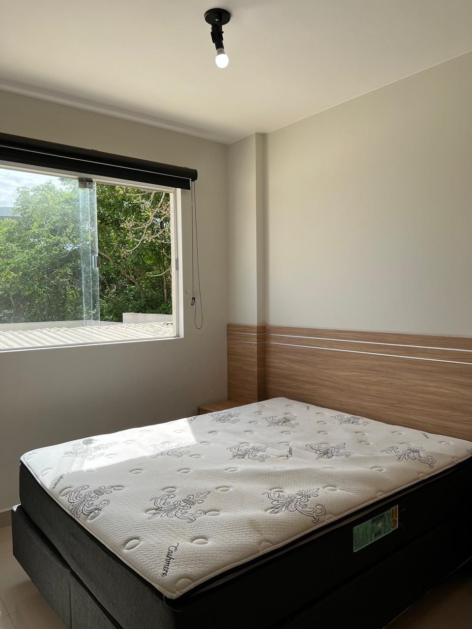 A bedroom with a bed, a window, and a ceiling light.