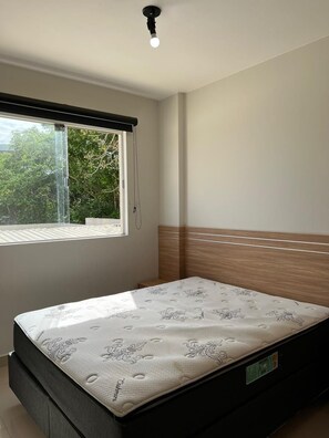A bedroom with a bed, a window, and a ceiling light. - Apto 2 Quartos p/ 8 - acesso ao rio (Rio Quente)