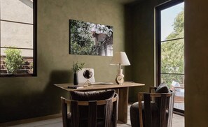 Ein Zimmer mit Esstisch, Stühlen, einer Lampe, einem Globus und einem gerahmten Bild an der Wand.