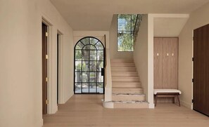 Ein Flur mit Holzboden, einer Wendeltreppe mit Sitzbank und einem großen Bogenfenster.
