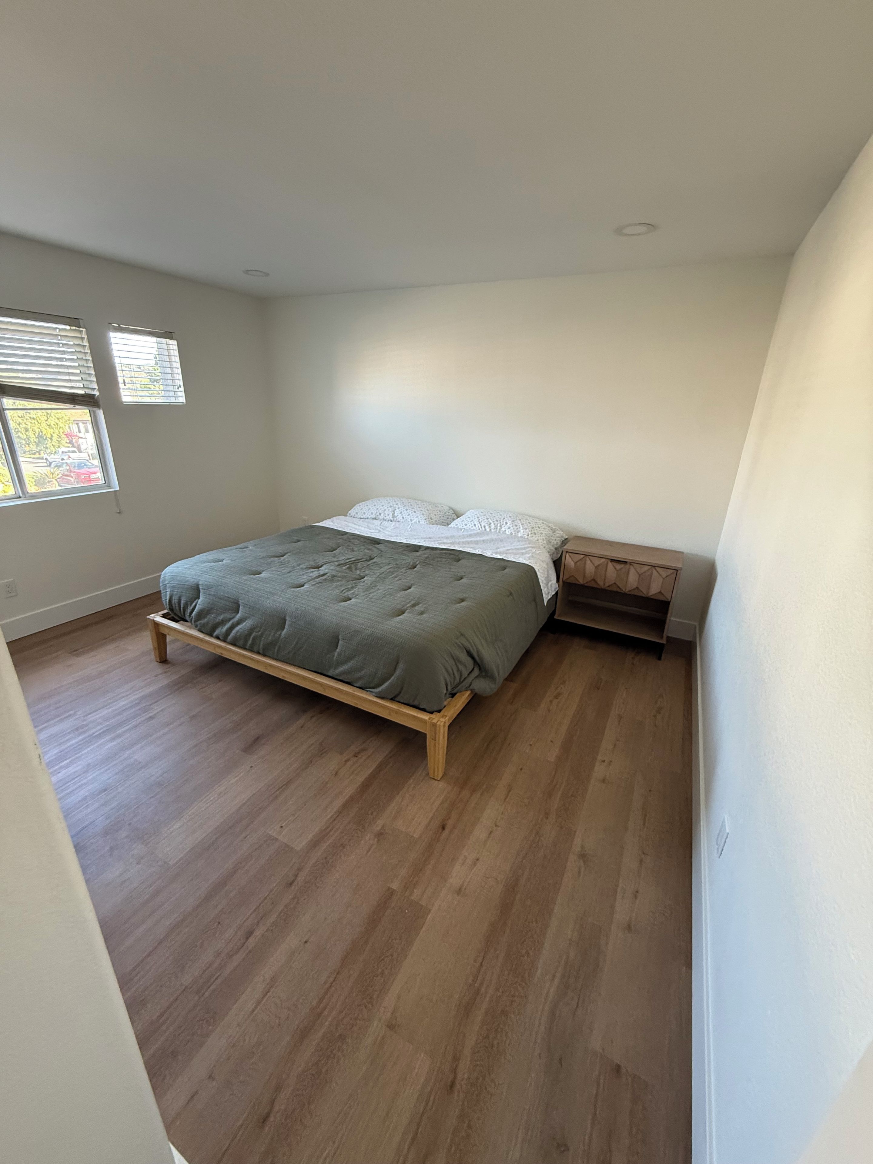Une chambre à coucher avec un lit, une table de chevet et une fenêtre.