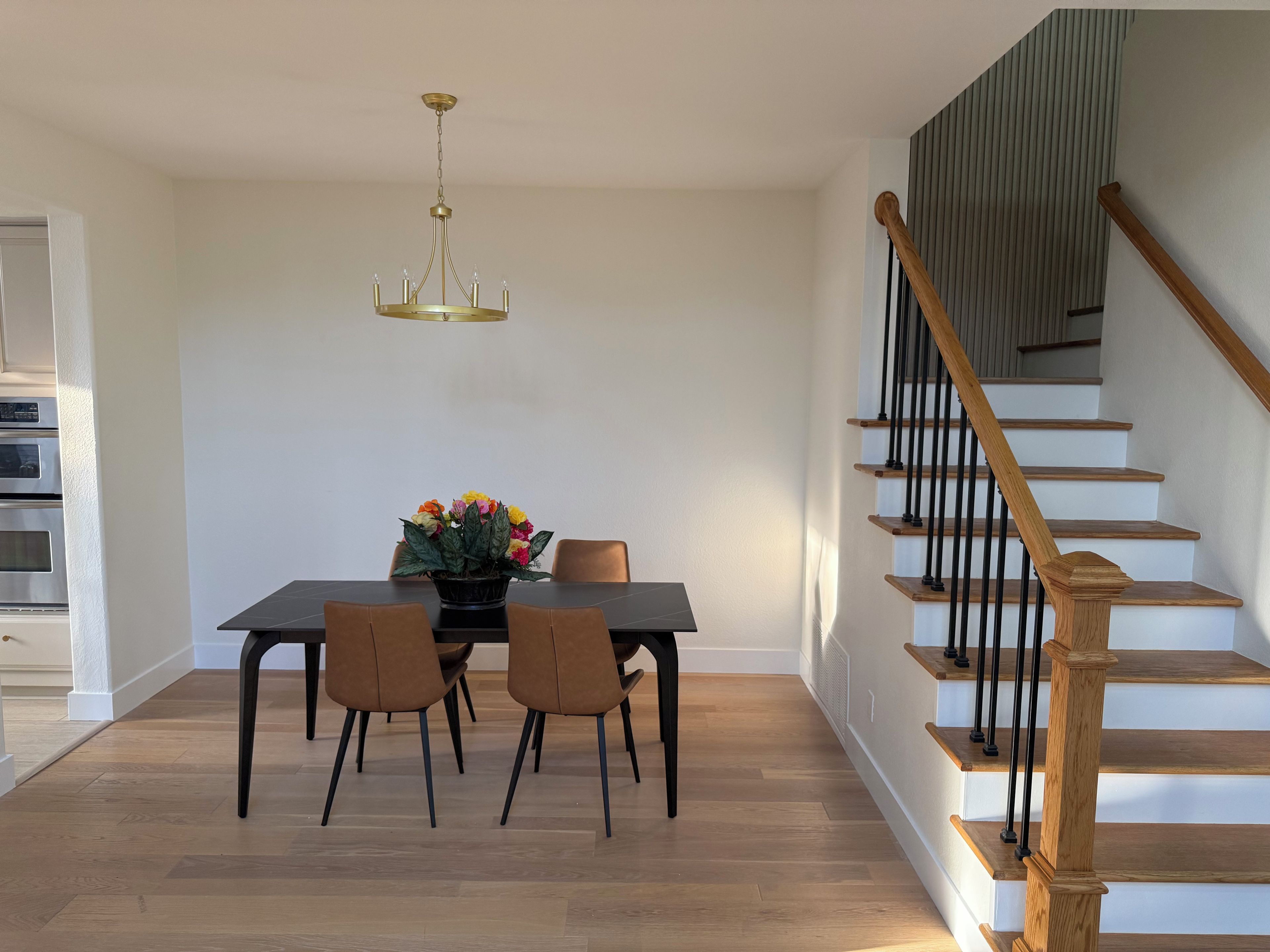 Un espace repas comprenant une table, des chaises, un lustre et un escalier.