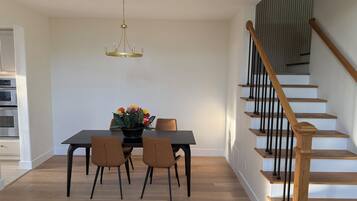 Un espace repas comprenant une table, des chaises, un lustre et un escalier.