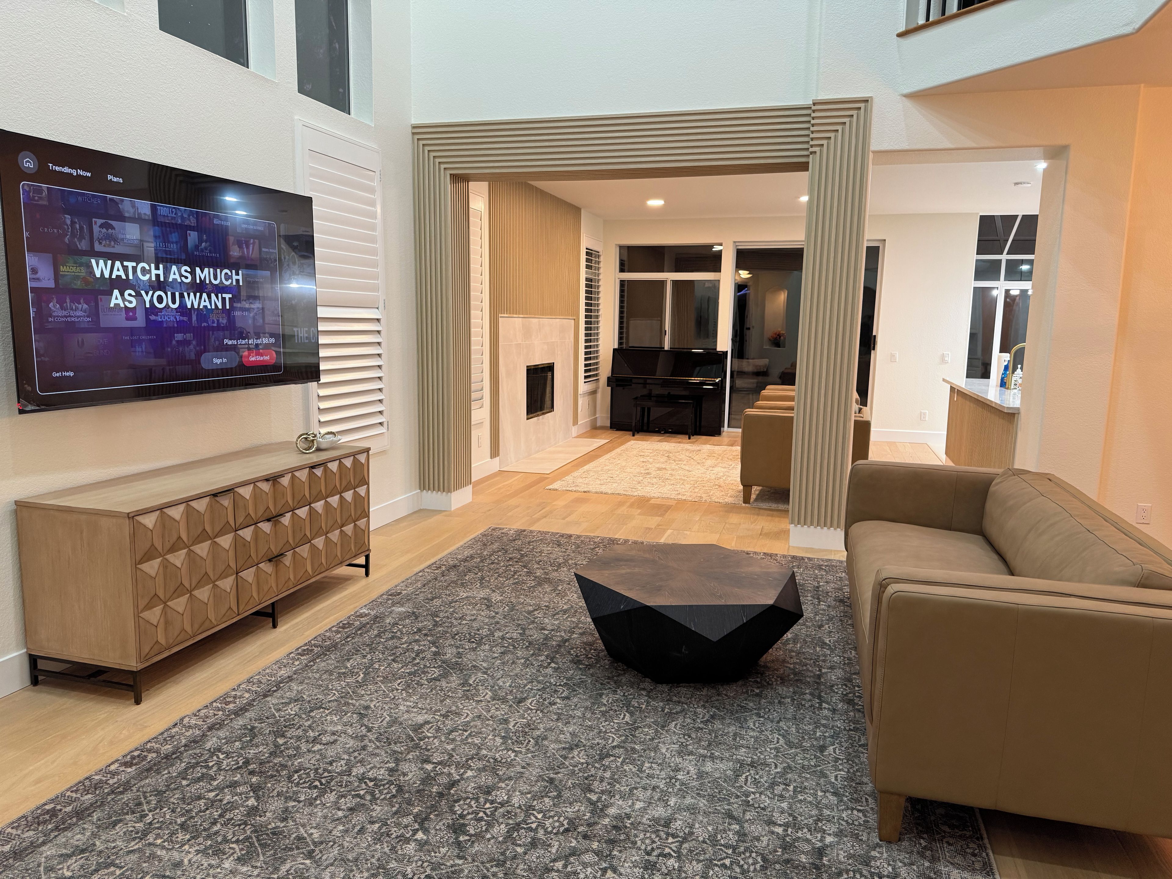 Un salon moderne avec un téléviseur à écran plat, une console, une table basse et un canapé.