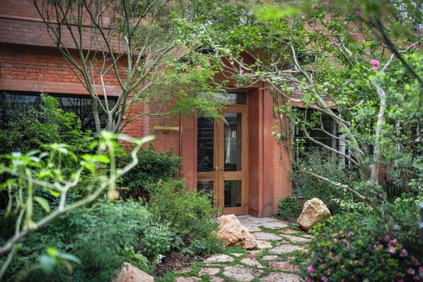 A brick building with a wooden door and a stone pathway leading to it. - Hylla Casa (Chongqing)
