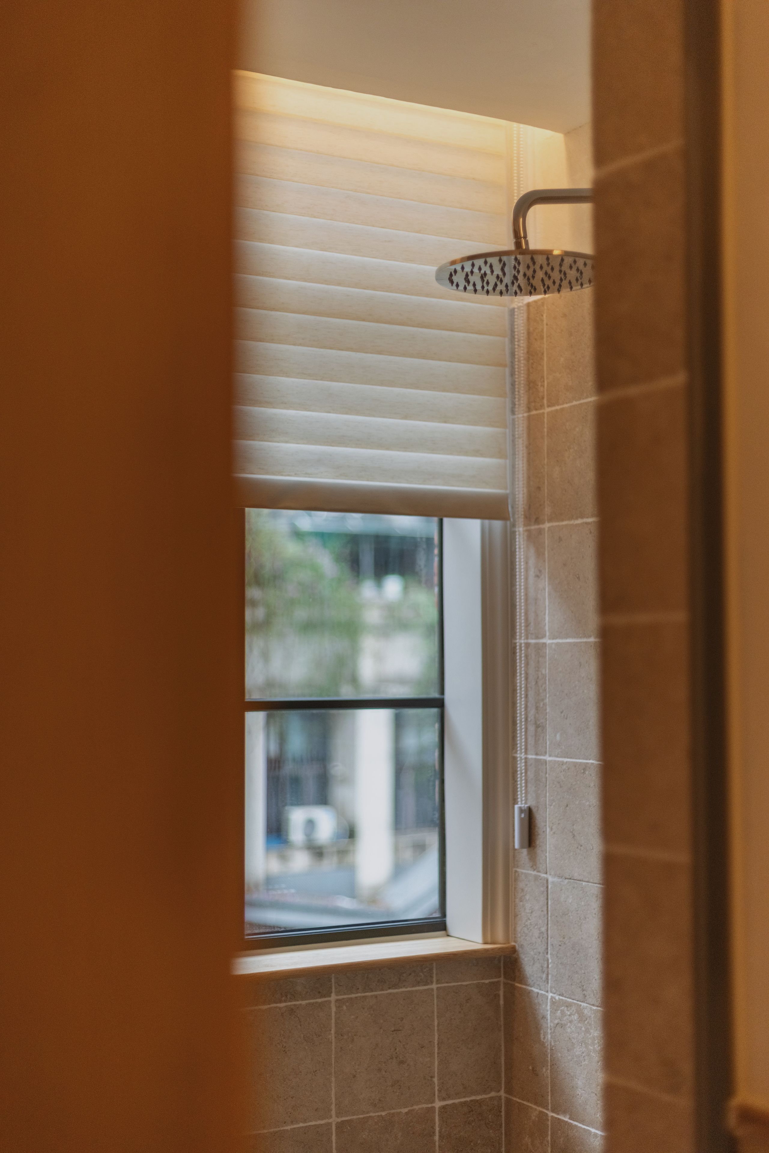 A bathroom with a shower, a window, and a view of the outside.