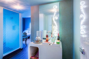 Habitació d'hotel amb un llit, un taulell de bany i un mirall amb llums decoratives.