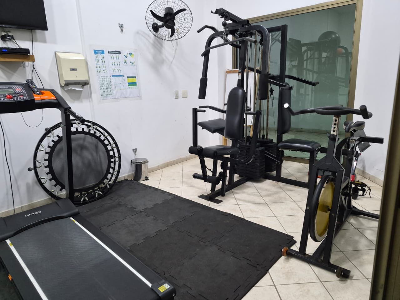 Un gimnasio con caminadora, elíptica y máquinas de pesas.