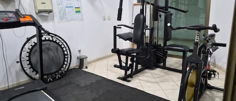 A gym with a treadmill, elliptical, and weight machines.