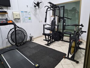 Un gimnasio con caminadora, elíptica y máquinas de pesas.
