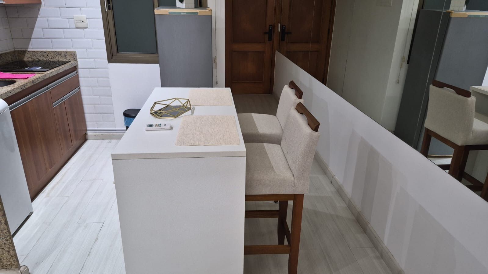 Eine kleine Küche mit weißer Arbeitsplatte, einem Tisch und einem Stuhl.