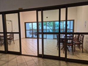 A room with a large sliding glass door leading to an outdoor area with a dining table and chairs. - Luxury Apartment Near Ipanema Beach Rio de Janeiro (Rio de Janeiro)