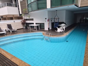 An indoor swimming pool with a tiled edge, surrounded by white lounge chairs and a table. - Luxury Apartment Near Ipanema Beach Rio de Janeiro (Rio de Janeiro)