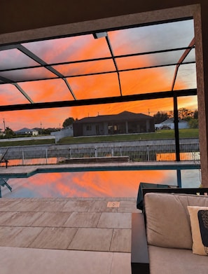 Een buitenzwembad met uitzicht op een gebouw en een zonsondergang.