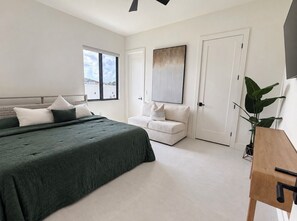 Een slaapkamer met een bed, een bank, een bureau en een groot raam.