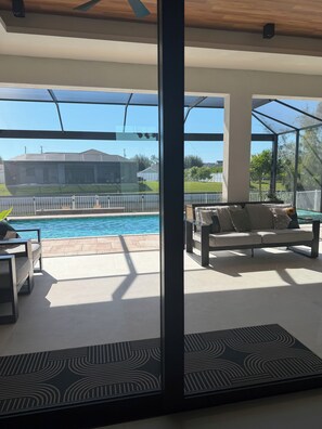 Un espace de vie extérieur moderne comprenant une piscine, un canapé et une table à manger.