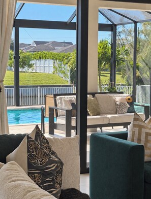 Une chambre avec vue sur une piscine, un canapé et un fauteuil.