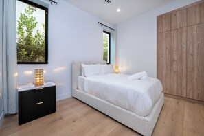A bedroom with a bed, bedside table, and a wardrobe. - Thayer Abode By Alora Reserve (Los Angeles)